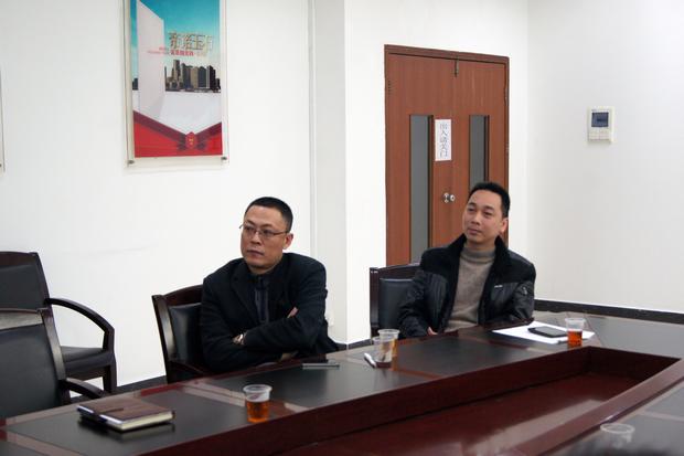 图5、hjc888黄金城抛光砖销售副总张彦（左一）、hjc888黄金城广东线销售副总庞永江（右一）认真寓目参评专卖店幻灯片播放效果